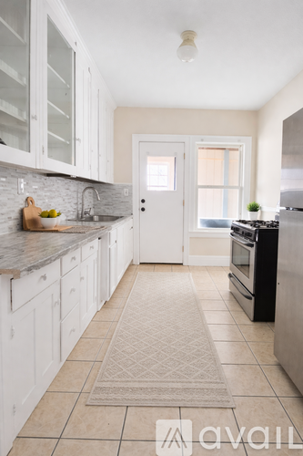 A kitchen with white cabinets and a beige rug on the floor.