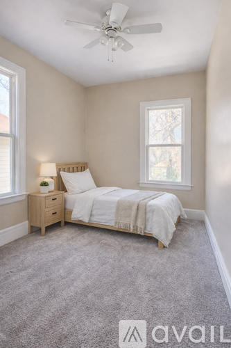 A bedroom with a bed, nightstand, and window.