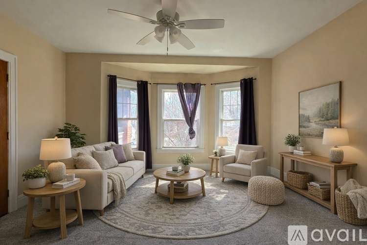 A living room with a couch, two chairs, a table, and a ceiling fan.