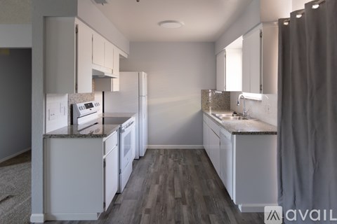 A kitchen with white cabinets and a wooden floor.