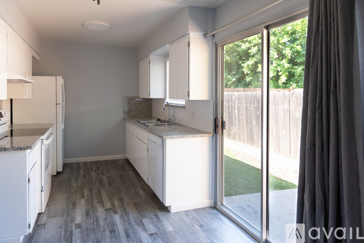 A kitchen with white cabinets and a wooden floor.