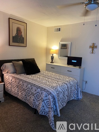 A bedroom with a bed, dresser, and a ceiling fan.