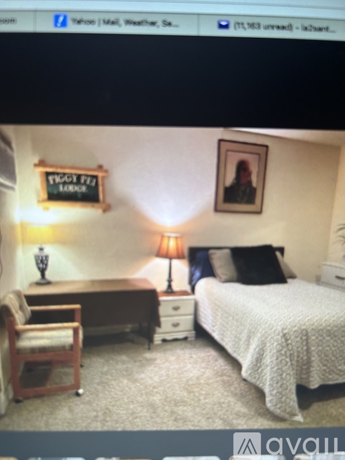 A bedroom with a bed, desk, chair, and a lamp.