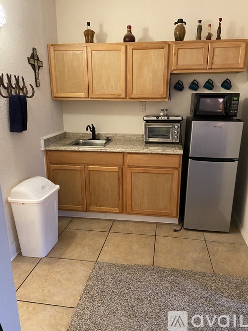 A kitchen with wooden cabinets and a white trash can.