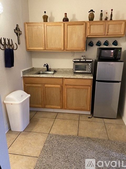 A kitchen with wooden cabinets and a white trash can.
