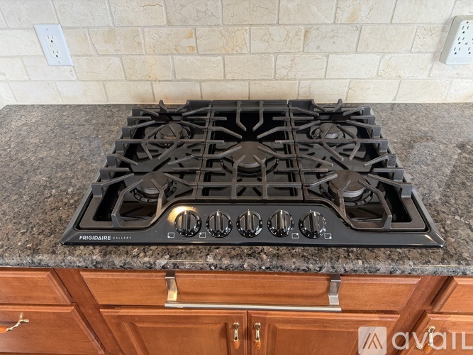 A Frigidaire gas stove top is on a granite countertop.