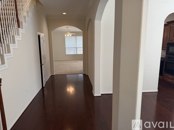 A long hallway with a staircase on the left and a kitchen area on the right.