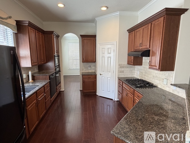 A kitchen with wooden cabinets and a black refrigerator.