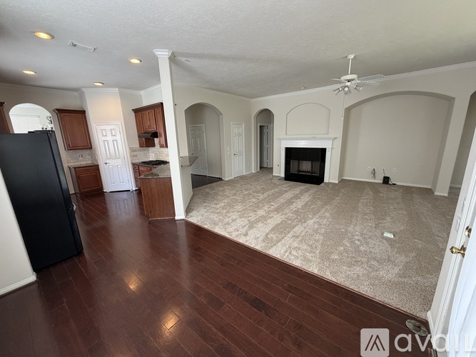 A spacious living room with wood flooring and a fireplace.
