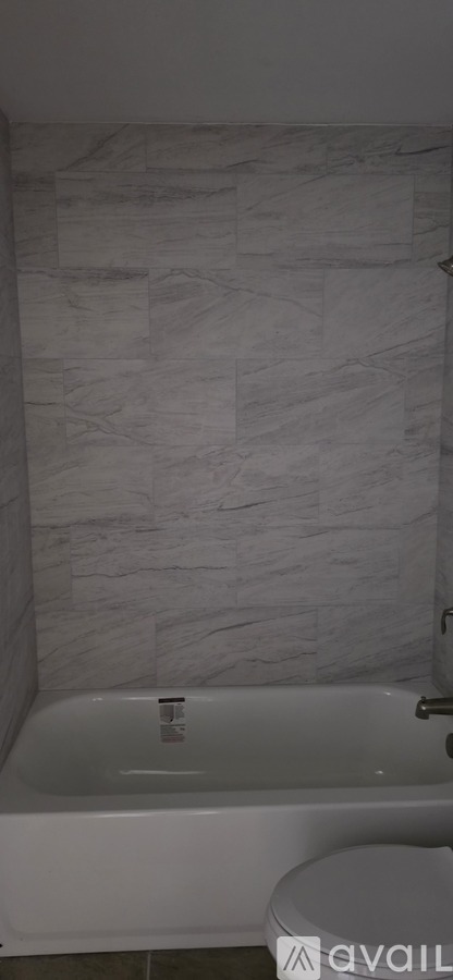 A white bathtub in a bathroom with a marble wall.