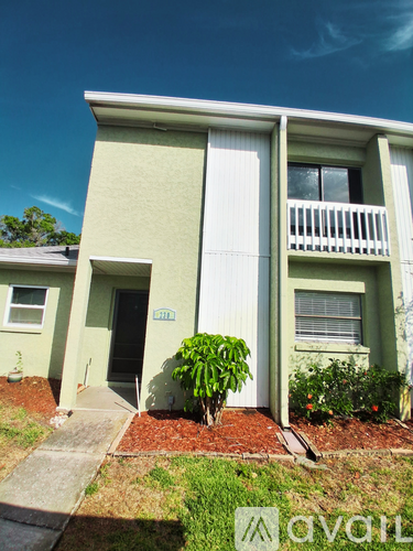 A green two-story house with a balcony on the second floor.