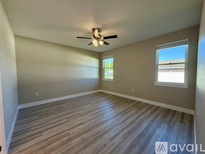 A spacious room with wooden flooring and a ceiling fan.
