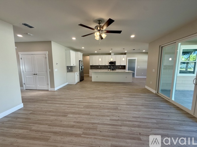 A spacious living room with a ceiling fan and hardwood flooring.