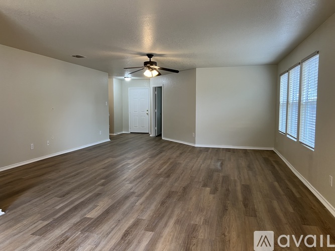 A spacious room with wooden flooring and a ceiling fan.
