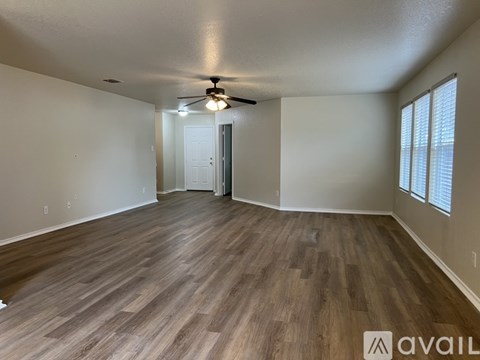 A spacious room with wooden flooring and a ceiling fan.