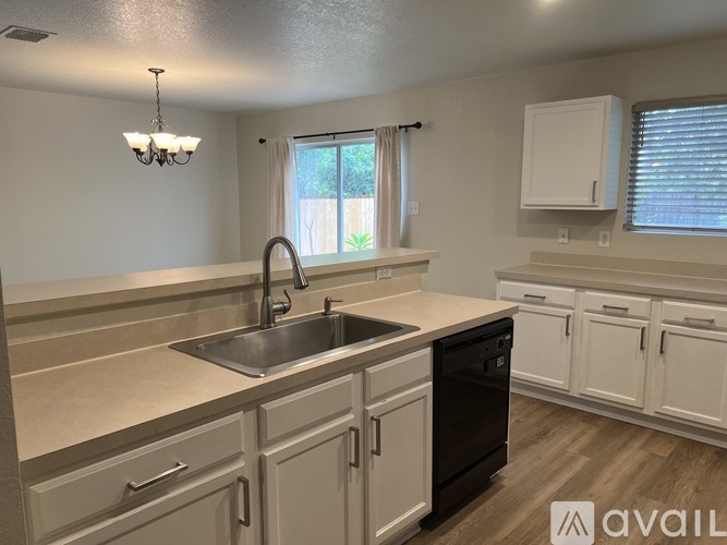 A kitchen with a sink, dishwasher, and cabinets.