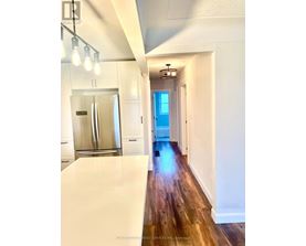A long hallway with a refrigerator on the left and a door at the end.