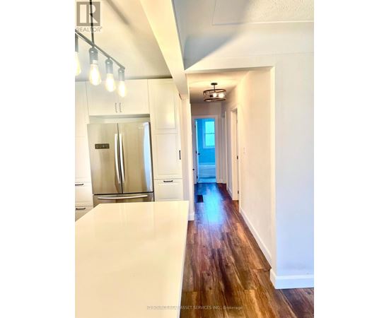 A long hallway with a refrigerator on the left and a door at the end.