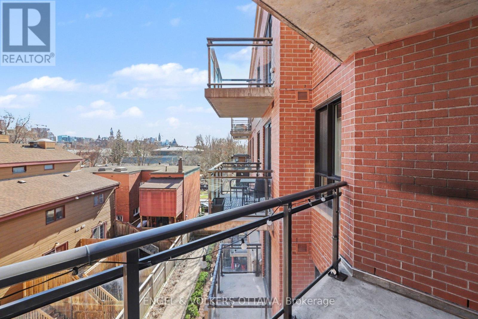A balcony with a metal railing overlooks a view of other buildings.