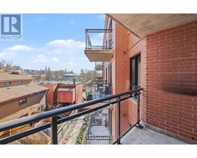 A balcony with a metal railing overlooks a view of other buildings.