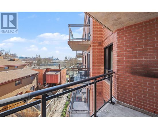 A balcony with a metal railing overlooks a view of other buildings.