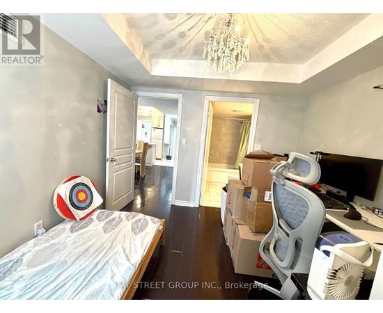 A bedroom with a bed, desk, and chair with boxes on the floor.