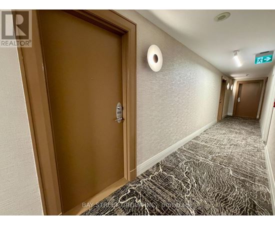 A hallway with a marble patterned floor and a brown door.