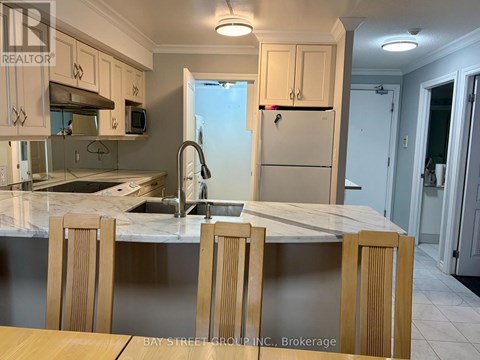 A kitchen with a marble countertop and wooden chairs.