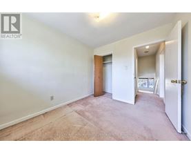 A bedroom with a carpeted floor and a door leading to a balcony.