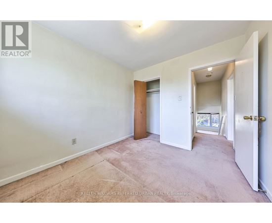 A bedroom with a carpeted floor and a door leading to a balcony.