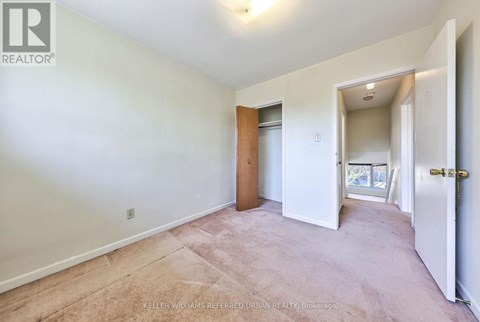 A bedroom with a carpeted floor and a door leading to a balcony.