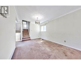 A spacious room with a staircase leading to the second floor.