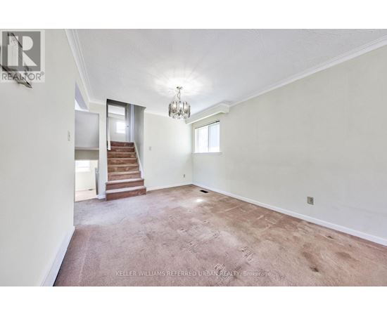 A spacious room with a staircase leading to the second floor.