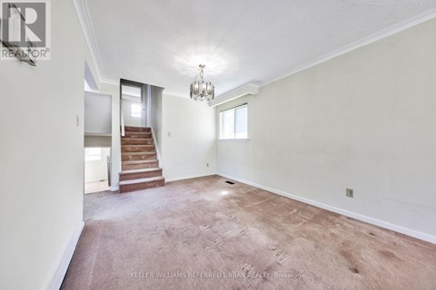 A spacious room with a staircase leading to the second floor.