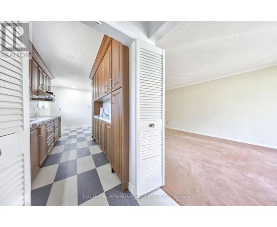 A kitchen with a checkered floor and wooden cabinets.