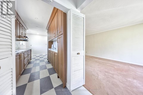A kitchen with a checkered floor and wooden cabinets.