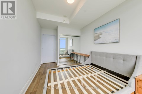 A living room with a grey couch and a painting on the wall.