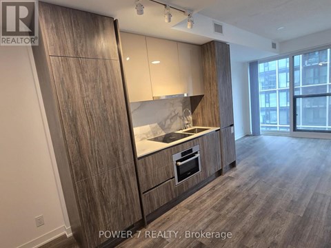 A kitchen with wooden cabinets and a marble backsplash.
