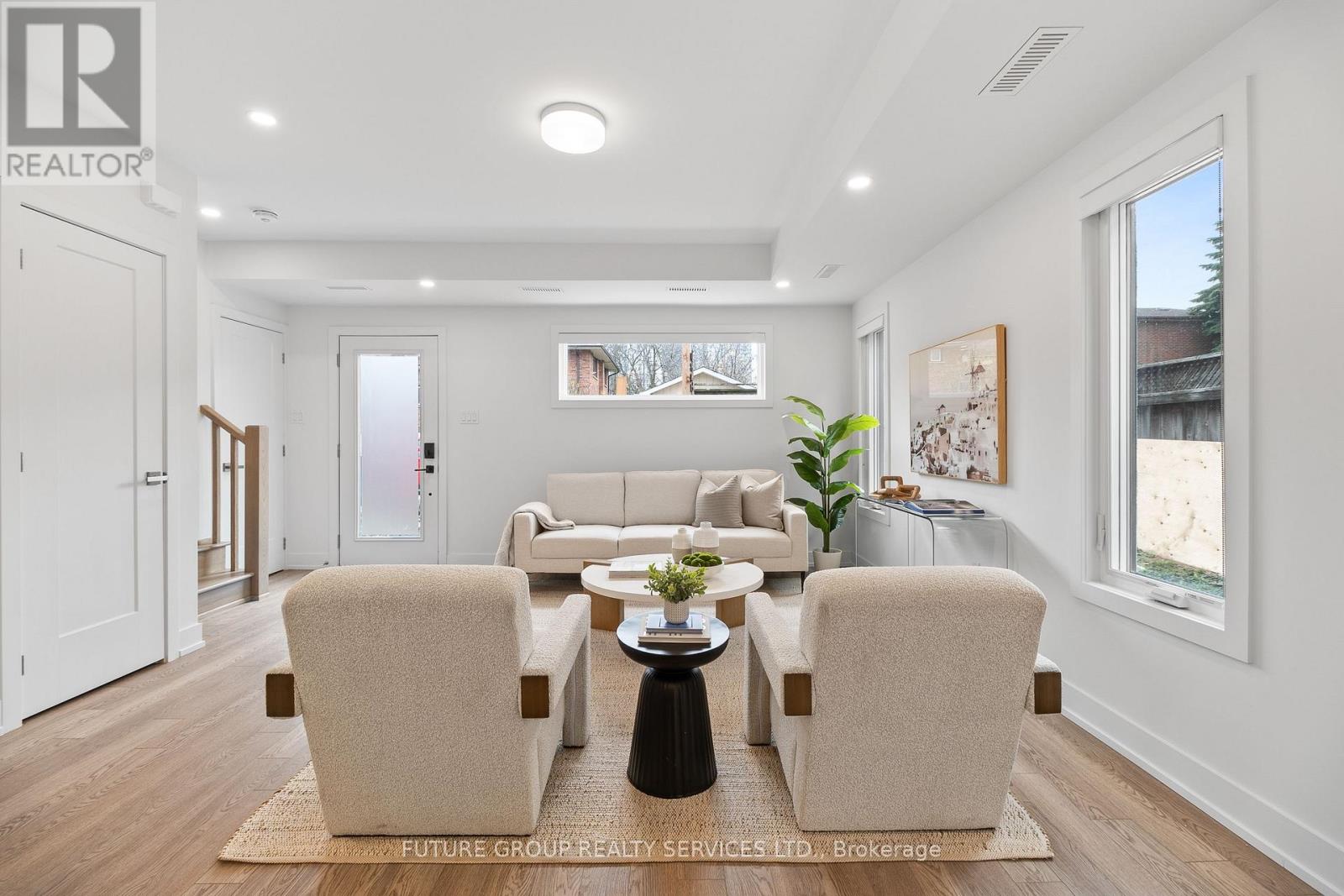 A well-lit living room with a beige sofa and matching armchairs.
