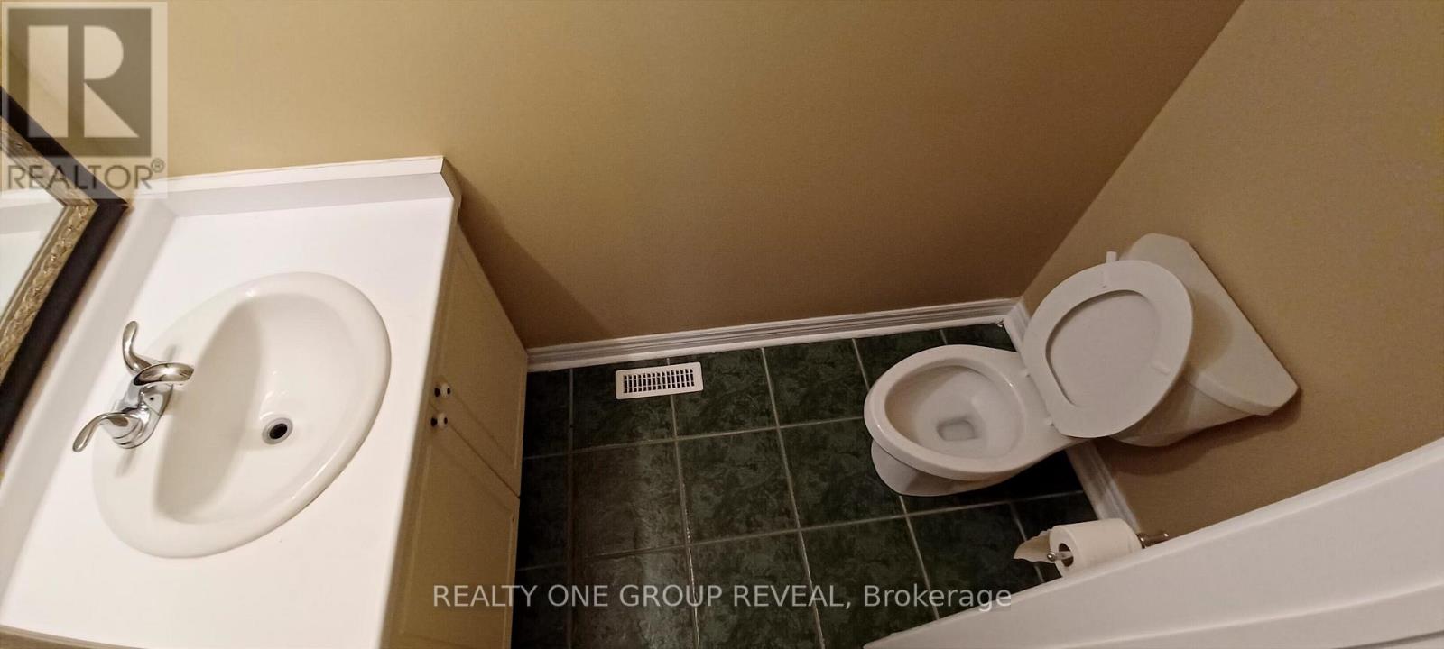 A white toilet with the lid up in a small bathroom.
