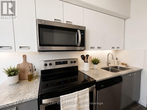 A modern kitchen with a black oven and white cabinets.
