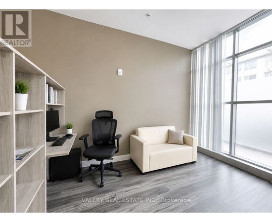 A room with a desk, chair, and couch with a window in the background.
