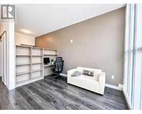 A room with a white couch, a black chair, and a desk with a computer.