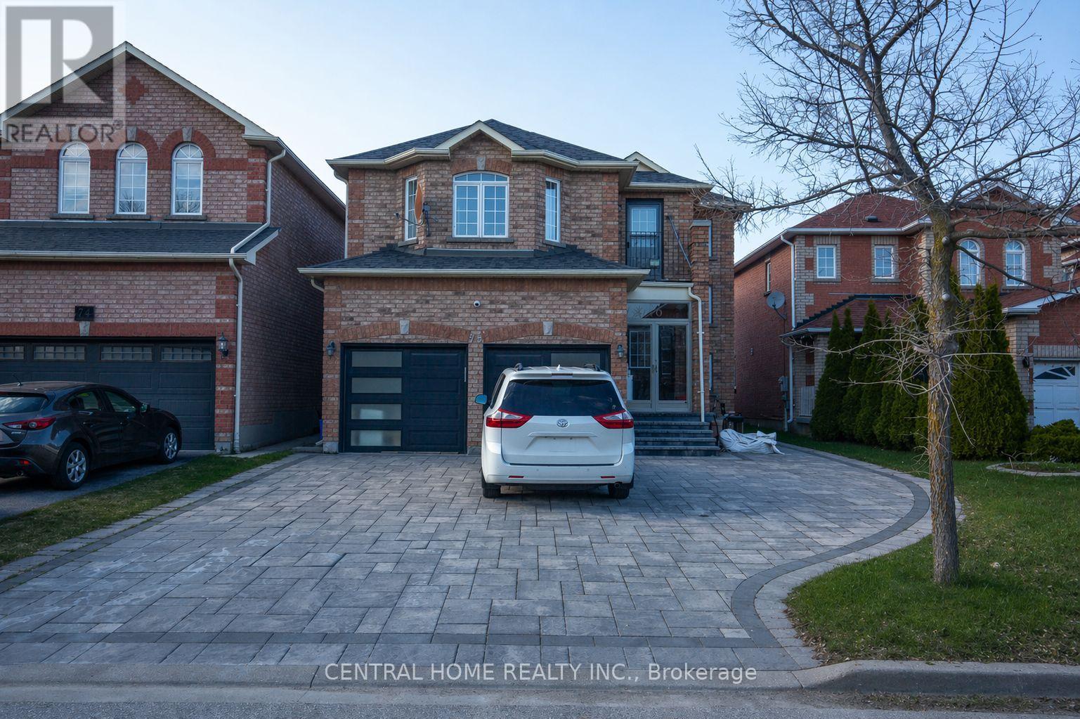 A car is parked in front of a house with a brick facade.