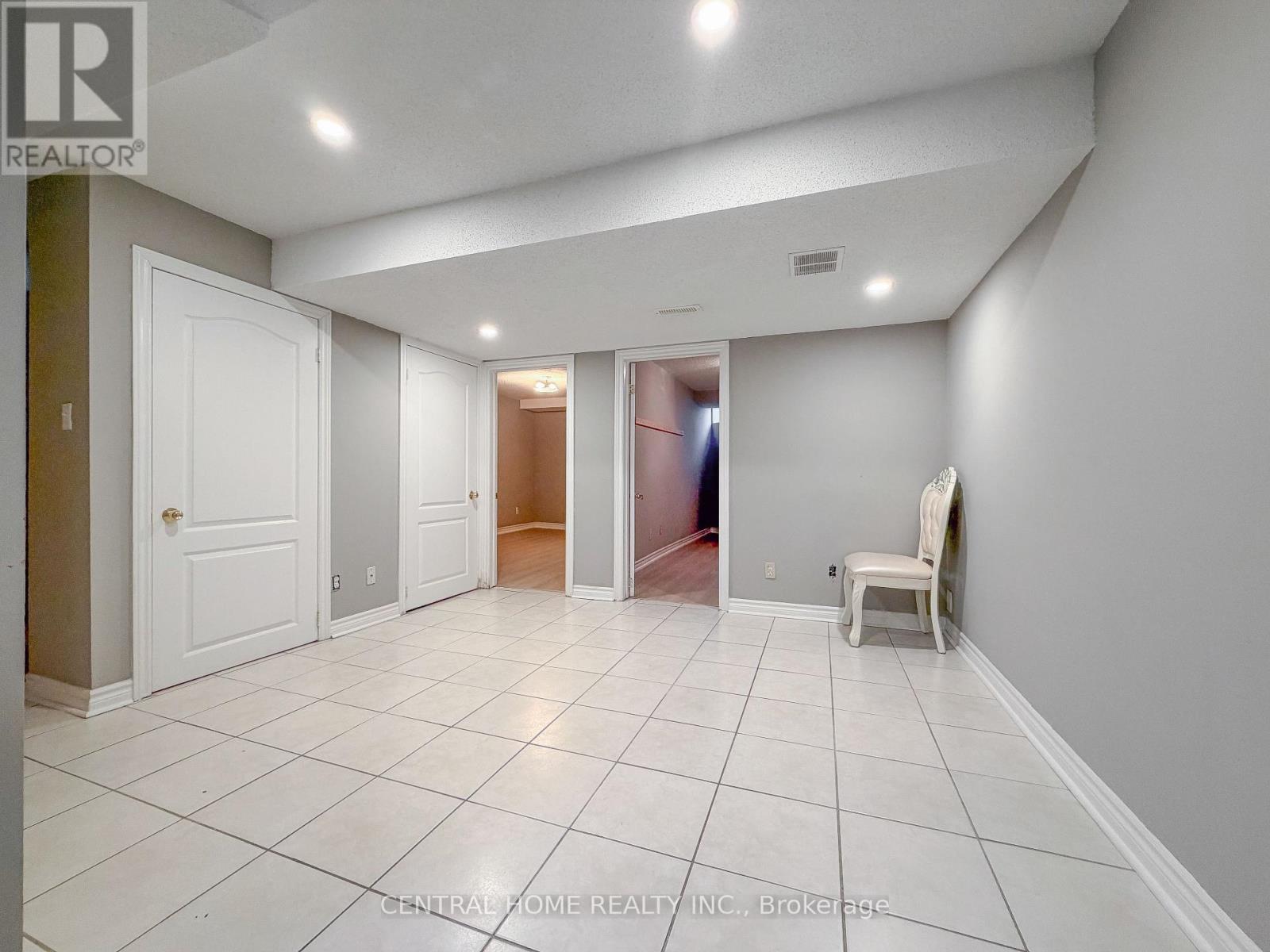 A spacious room with white tile flooring and a white chair.
