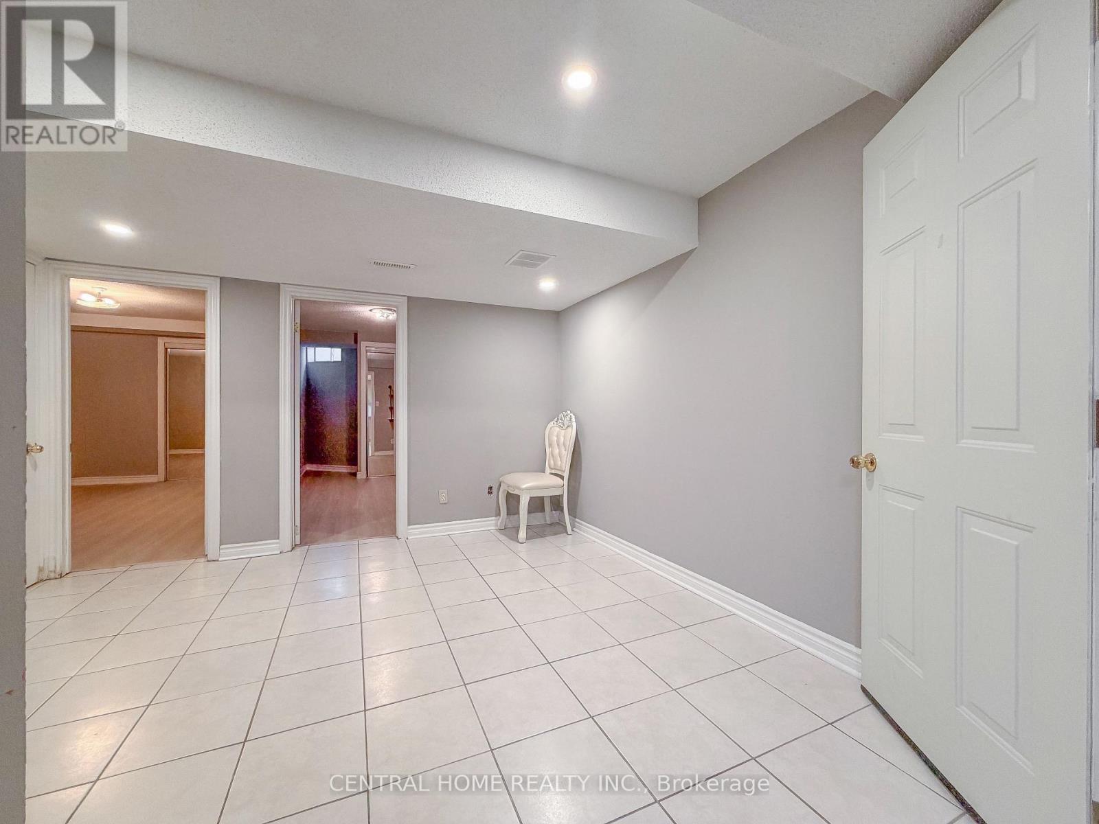 A white chair is placed in the middle of a white tiled room.