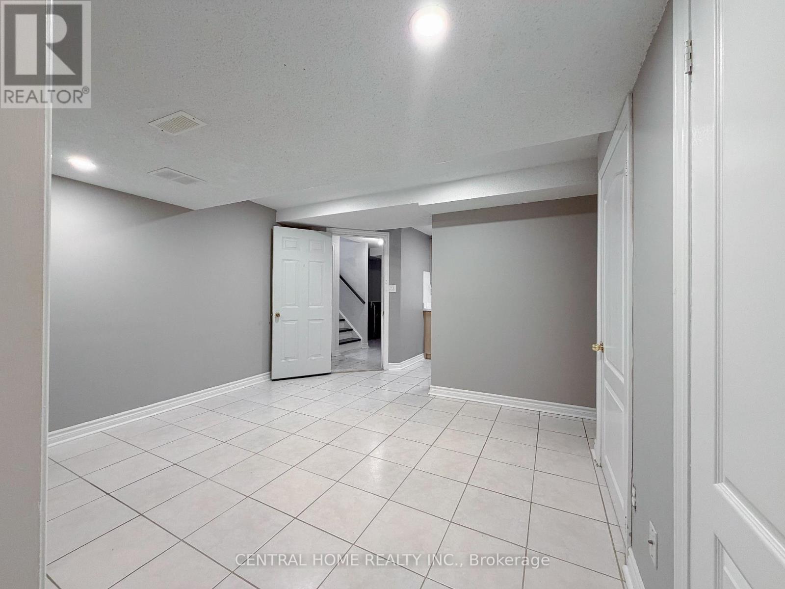 A spacious room with white tile flooring and a white door.