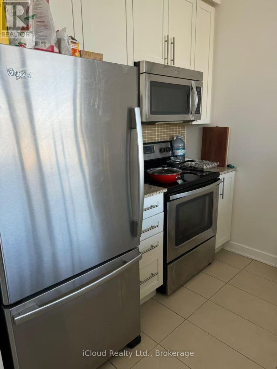 A kitchen with a stainless steel refrigerator and a microwave above a stove.