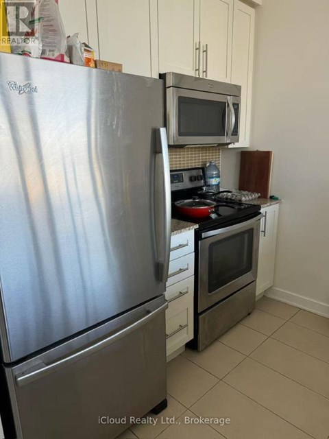 A kitchen with a stainless steel refrigerator and a microwave above a stove.