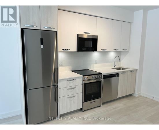 A kitchen with a refrigerator, oven, and microwave.